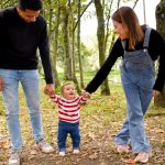 A joyful family enjoys a walk under lush green trees in the park.